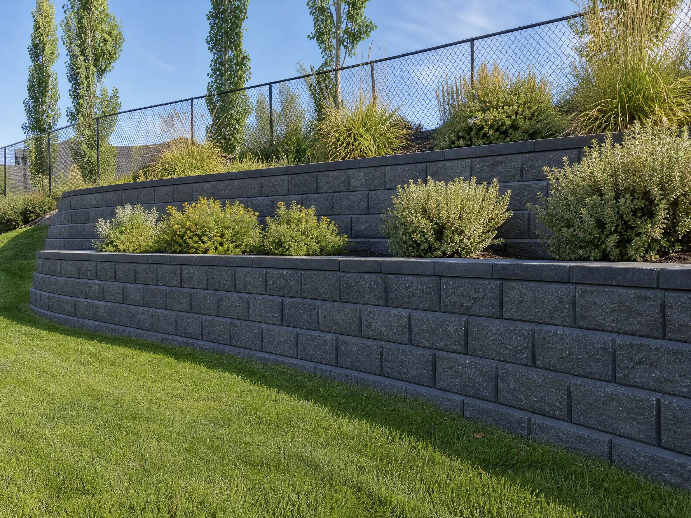 A tiered block retaining wall holding a graded slope in a Saskatoon, SK back yard