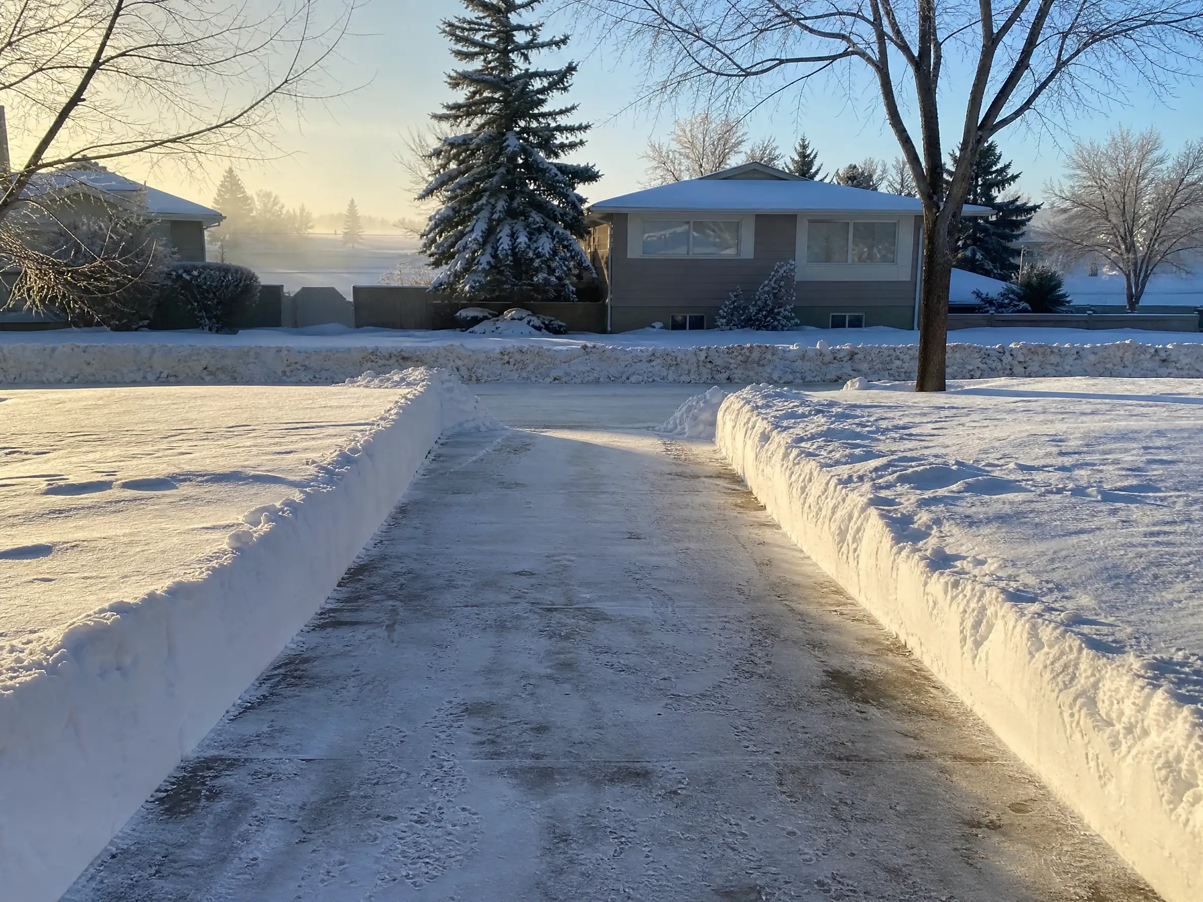 A residential driveway cleared of deep snow on a winter morning in Saskatoon, SK